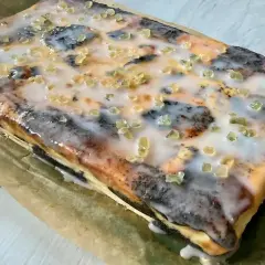 Seromakowiec z gotowej masy makowej i sera z wiaderka, bez spodu, polany lukrem i posypany kandyzowaną skórką pomarańczową.