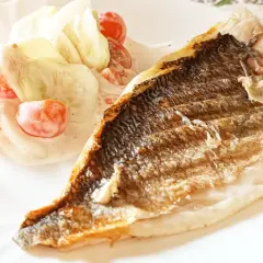 Chrupiąca dorada z grilla podana z orzeźwiającą sałatką z pomidorków i ogórka w sosie śmietanowym.