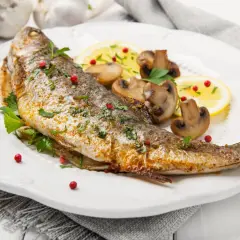 Pstrąg tęczowy przepis: pieczona ryba z cytryną, pieczarkami i natką pietruszki, posypana różowym pieprzem.