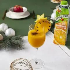 Aromatyczny likier pomarańczowy z goździkami i anyżem, ozdobiony plasterkiem pomarańczy i gwiazdką. Obok karton soku pomarańczowego.