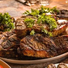 Szaszłyki z karkówki, grillowane, soczyste i aromatyczne, ułożone na białym talerzu, ozdobione świeżą natką pietruszki.
