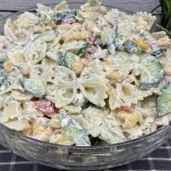 Pyszna, kremowa najlepsza sałatka z makaronem farfalle, ogórkiem, kukurydzą i ziołami.