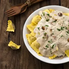 Ravioli z grzybami w sosie śmietana kremówka, posypane natką pietruszki.