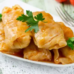Talerz pełen gołąbków w sosie pomidorowym, udekorowany natką pietruszki. Pyszne danie, które warto znać pod kątem gołąbki kcal.