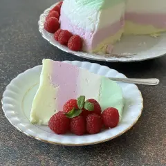 Pyszna pianka z galaretki i jogurtu, udekorowana malinami i miętą, na talerzyku.