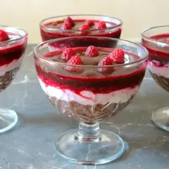 Pyszny deser z mascarpone i galaretką malinową, udekorowany świeżymi malinami, podany w eleganckich pucharkach.