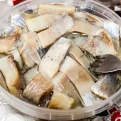 Pyszne śledzie na wielkanoc w zalewie, gotowe do podania. Widoczna jest też część bagietki.