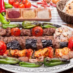 Turecka potrawa: grillowane mięso, bakłażany, pomidory i papryka na talerzu, obok ryż i pieczywo.