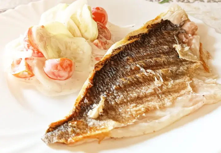Chrupiąca dorada z grilla podana z orzeźwiającą sałatką z pomidorków i ogórka w sosie śmietanowym.