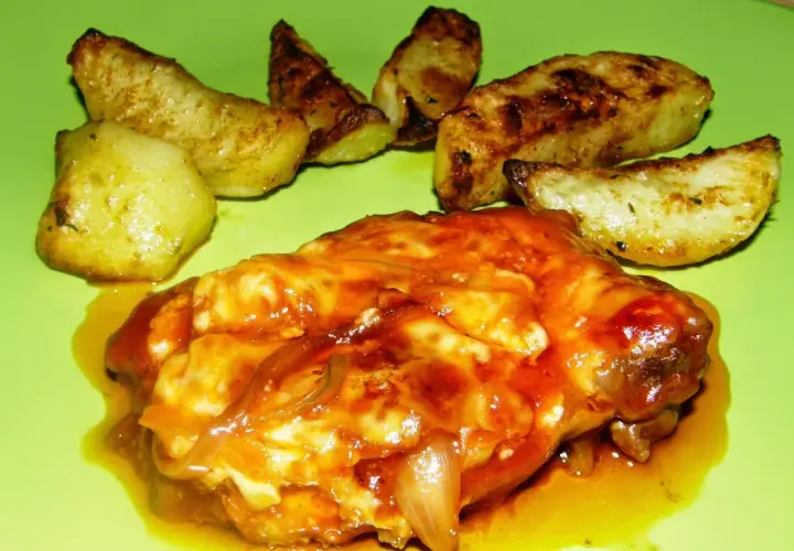 Karkówka pieczona w plastrach z majonezem i ketchupem, podana z pieczonymi ziemniakami. Pyszne danie na obiad.