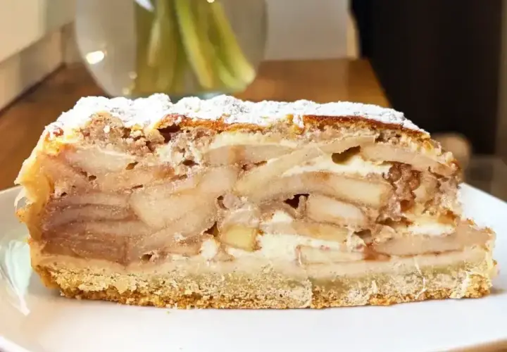 Pyszny kawałek szarlotki z warstwami jabłek i kremu, posypany cukrem pudrem. Idealny, by dowiedzieć się, ile piec szarlotkę.