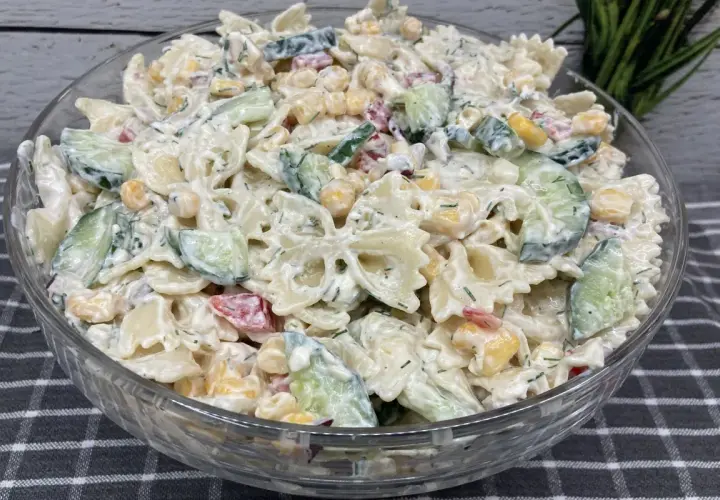 Pyszna, kremowa najlepsza sałatka z makaronem farfalle, ogórkiem, kukurydzą i ziołami.