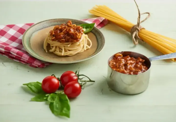 Porcja spaghetti z sosem bolońskim, obok pomidorki i bazylia. Pytanie: czy można zamrozić sos z mięsem?
