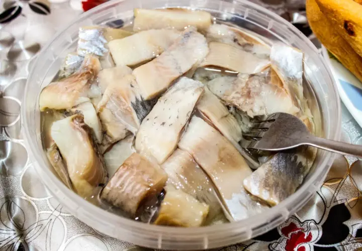 Pyszne śledzie na wielkanoc w zalewie, gotowe do podania. Widoczna jest też część bagietki.