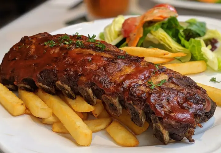 Soczyste żeberka w sosie BBQ, podane z chrupiącymi frytkami i świeżą sałatką. Prawdziwa uczta dla podniebienia!