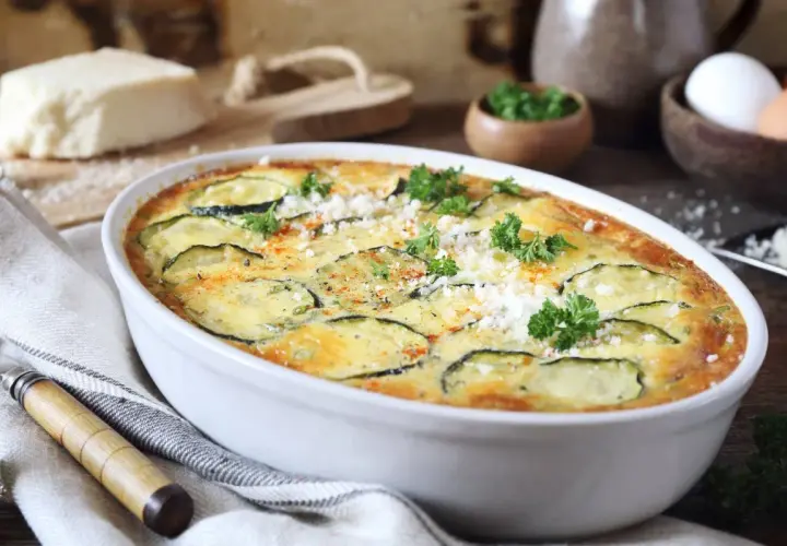 Szybka i prosta zapiekanka z cukinii, udekorowana natką pietruszki i parmezanem, gotowa do podania.