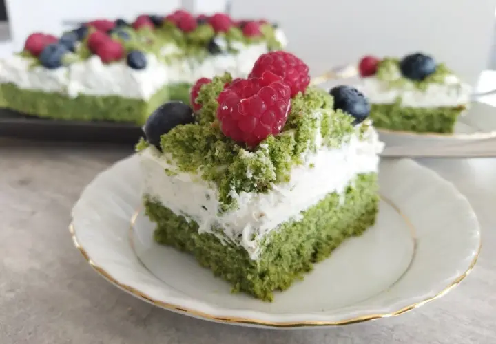 Zielony, puszysty biszkopt przełożony kremem z serkiem mascarpone, udekorowany malinami i borówkami. To ciasto leśny mech na dużą blachę, które zachwyca smakiem.