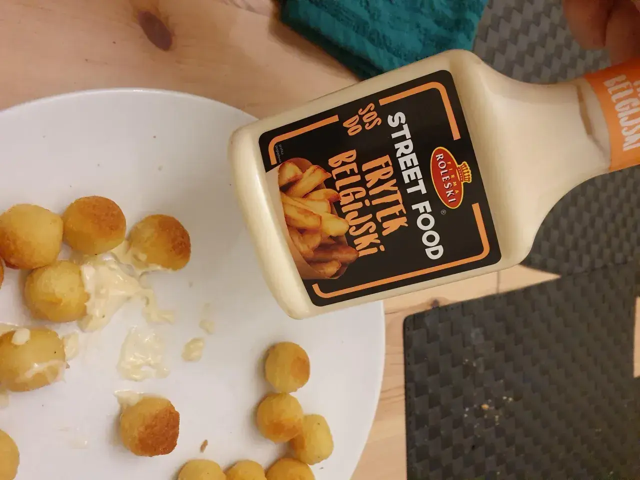 Kula frytek na talerzu, obok butelka sosu belgijskiego Street Food.