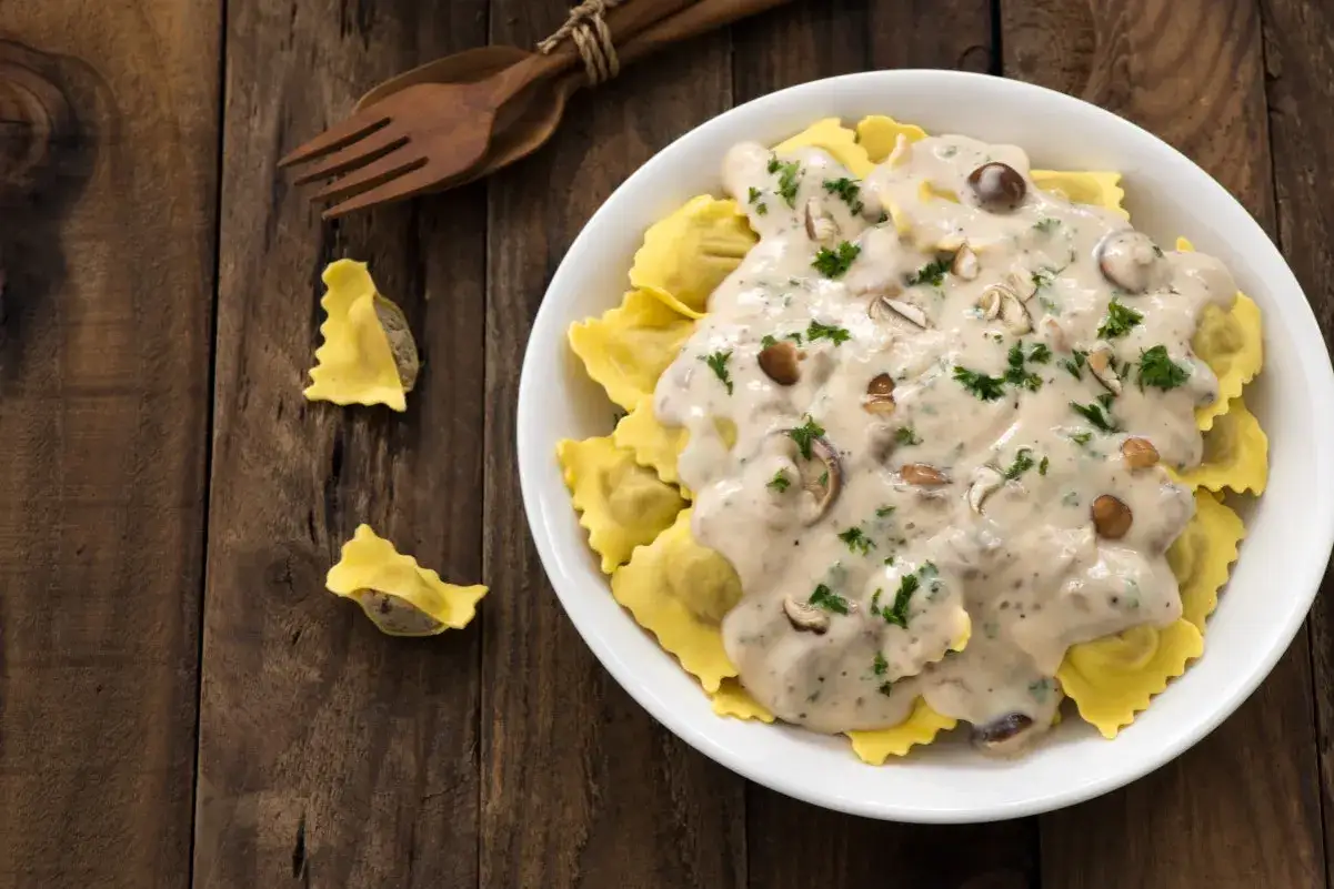Ravioli z grzybami w sosie śmietana kremówka, posypane natką pietruszki.