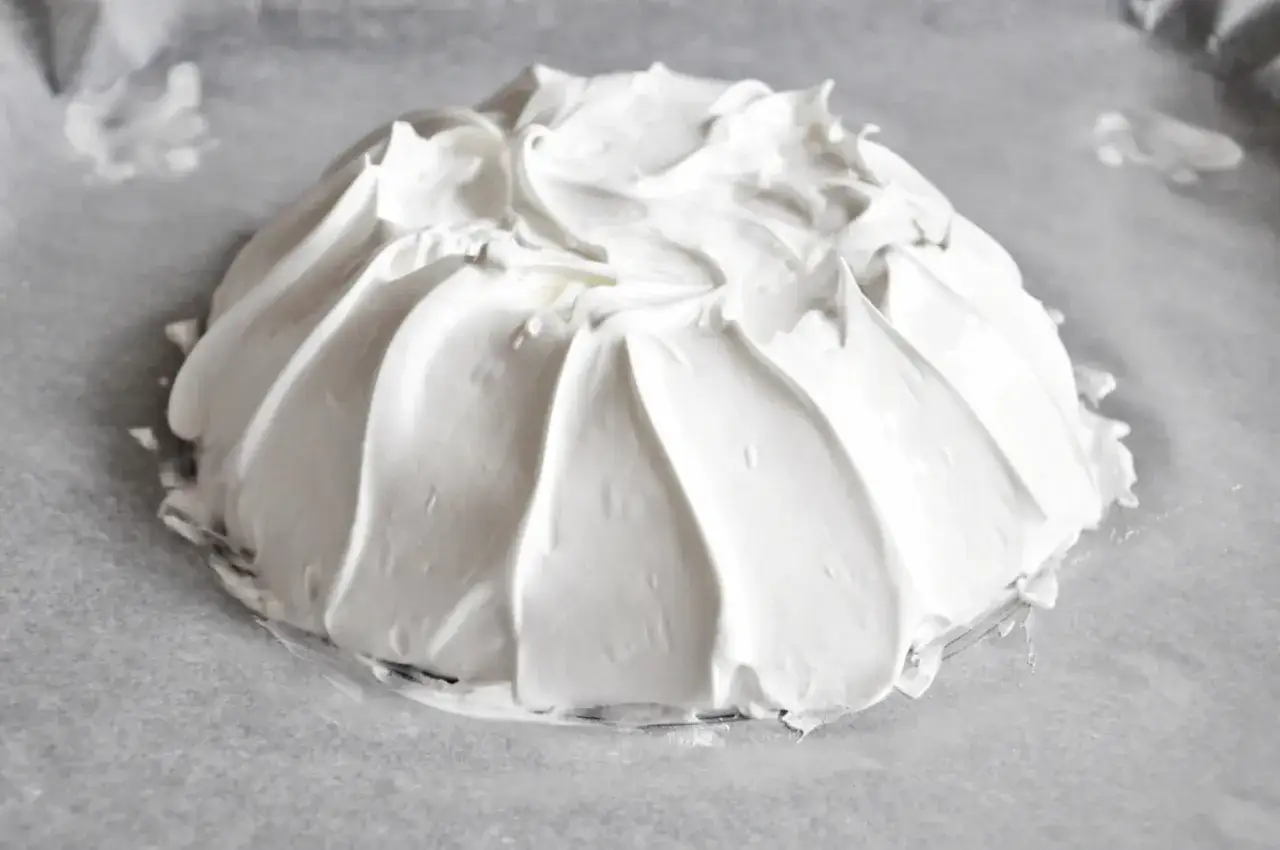 Beza pavlova która zawsze wychodzi, przygotowana na papierze do pieczenia. Jej puszysta, biała masa tworzy efektowne fale.