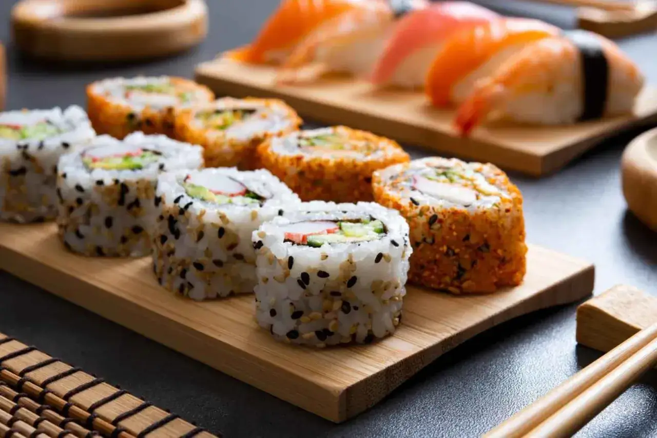 Uramaki z sezamem i pomarańczowe rolki z ikrą, obok nigiri z łososiem. Pyszne sushi czeka!